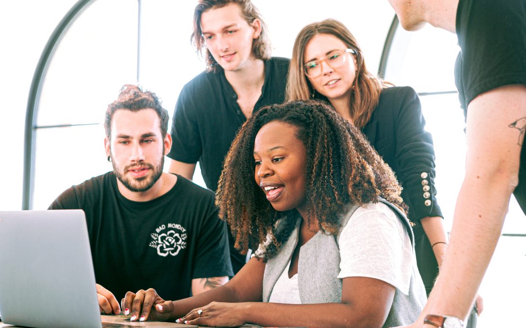 diverse start up team looking at a single laptop